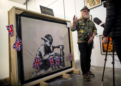 Ron English standing in front of aBanksy mural he recently bought andplans to whitewash as an act of protest